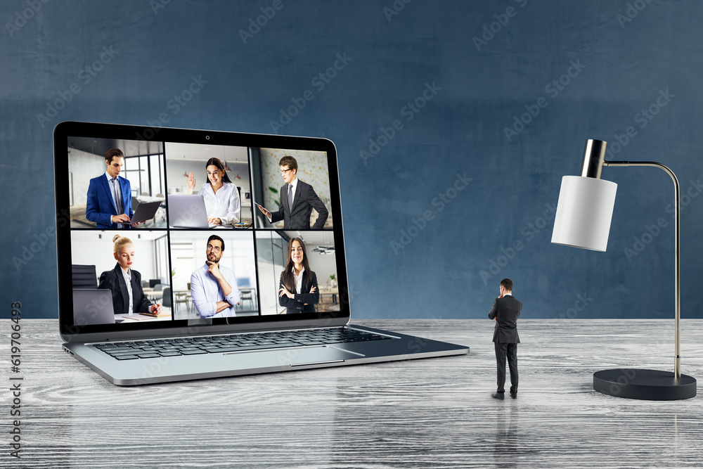 Poster attractive young european man standing on wooden desk with computer monitor on call with colleagues,