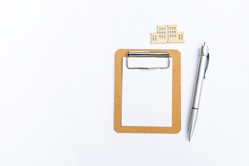 Blank white paper on wooden clipboard with silver color pen and building model isolate on white background, business or education concept
