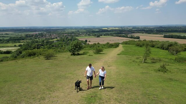 Drone Shot Of Loving Mature Couple Walking With Pet Dog Through Beautiful English Countryside In Oxfordshire England UK