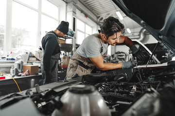 Fototapeta na wymiar Two male mechanics repairing car in car service
