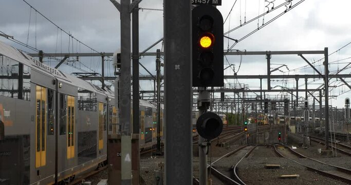 Camera focuses on yellow train signal as trains pass around. Urban metro transport show