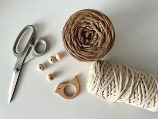 Weaving macrame. Materials for macrame. White and brown threads, wooden beads, scissors. Close-up...