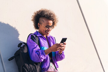 portrait of a stylish african american sportswoman using a mobile phone outdoors, concept of...
