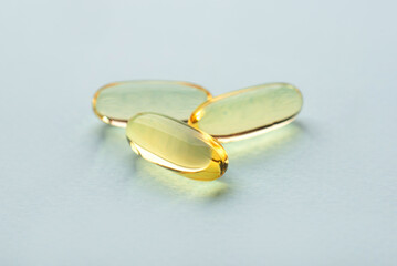 One omega 3 fish liver oil capsules on blue background. Close up, front view.