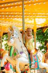 Blonde girl rides a horse in an amusement park.