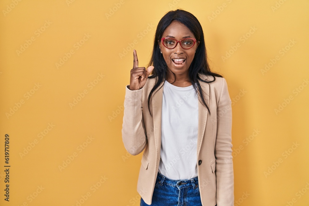 Poster african young woman wearing glasses pointing finger up with successful idea. exited and happy. numbe