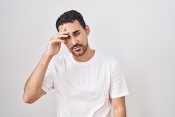 Fototapeta premium Handsome hispanic man standing over white background worried and stressed about a problem with hand on forehead, nervous and anxious for crisis