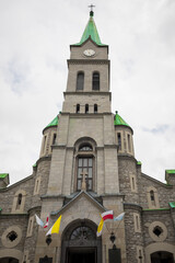 Tall church in a tourist town. Concrete facade and moisture of Poland. Chapel with a green roof.
