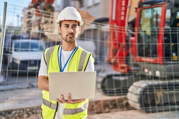 Young hispanic man architect using laptop at street