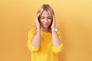 Young caucasian woman wearing yellow sweater with hand on head, headache because stress. suffering migraine.