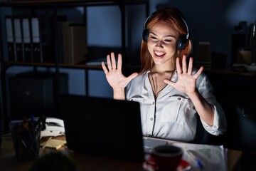 Young caucasian woman working at the office at night showing and pointing up with fingers number...