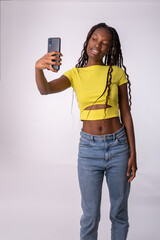 Mujer hermosa joven de color  que se hace un selfie con su teléfono con un fondo blanco. Chica...