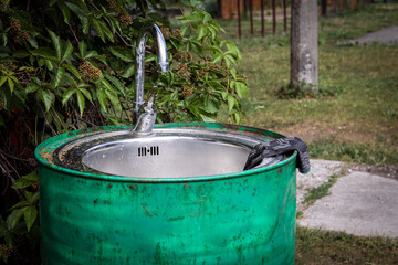 Outdoor faucet and sink in the green barrel. For washing hands and gardening