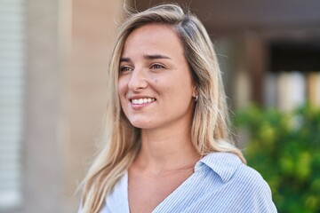 Young blonde woman smiling confident looking to the side at street