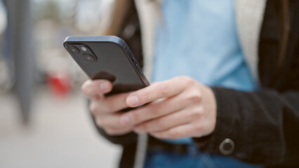 Young beautiful hispanic woman using smartphone at street