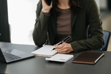 Obraz premium businesswoman hand working with new modern computer and writing on the notepad strategy diagram as concept morning light.