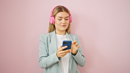 Young blonde woman business worker using smartphone wearing headphones over isolated pink background