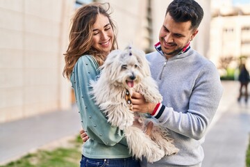 Man and woman holding dog hugging each other at street