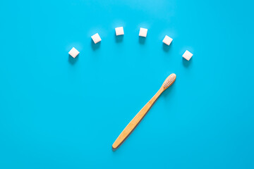 Toothbrush with sugar cubes on a blue background, flat lay.