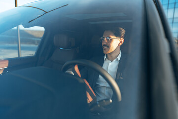 Naklejka premium Young businessman in elegant suit driving luxury car