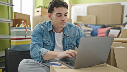 Young hispanic man using laptop and credit card sitting on sofa at new home