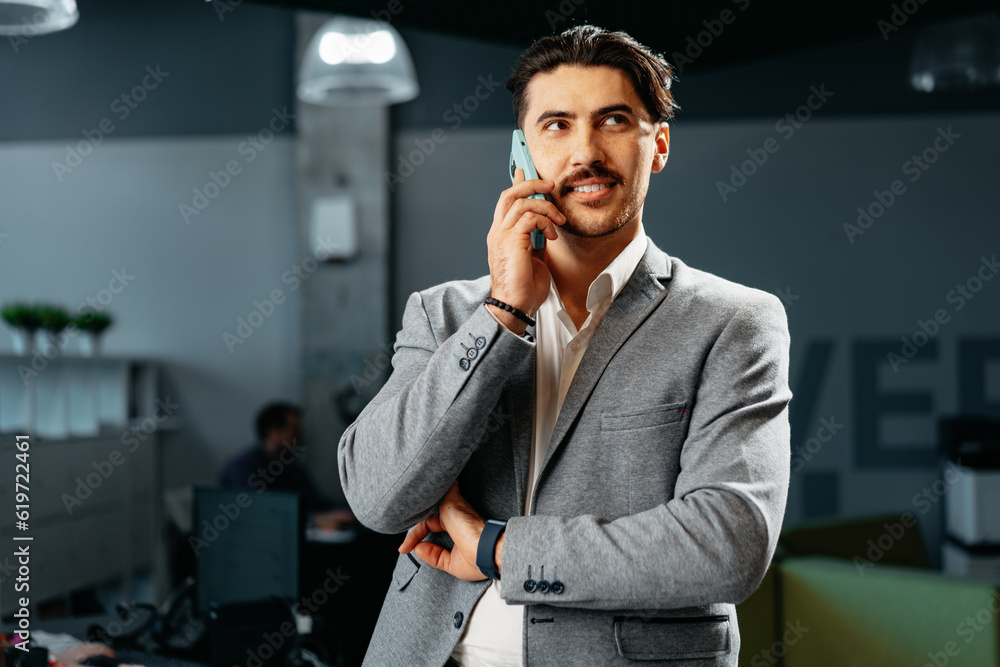 Poster Young arab businessman working at modern office, talking on mobile phone