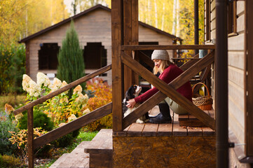 woman gardener relaxing in cozy autumn day, sitting on wooden stairs at house entryway. Enjoying...