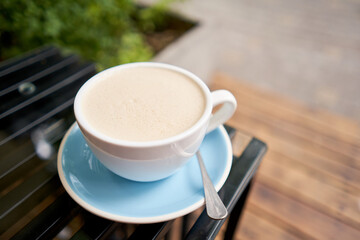 Cup of hot Peanut latte. The table in the coworking space of the coffee shop. A cup of coffee on the veranda on a sunny day. Coffee break at the cafe. Close-up