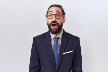 Hispanic man with beard wearing suit and tie afraid and shocked with surprise expression, fear and excited face.