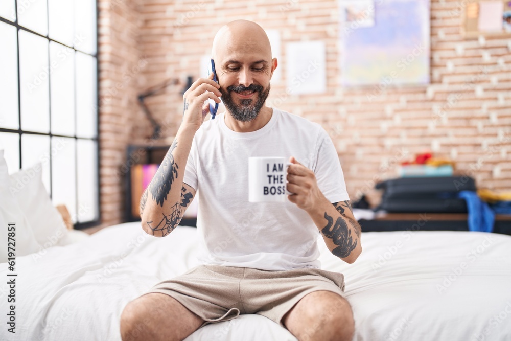 Canvas Prints Young bald man talking on smartphone drinking coffee at bedroom