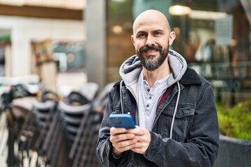 Young bald man smiling confident using smartphone at street