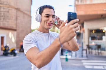 Fototapeta na wymiar Young hispanic man listening to music standing at street