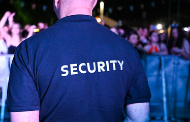 The security guard wears a T-shirt with the inscription security. A security guard stands in front...