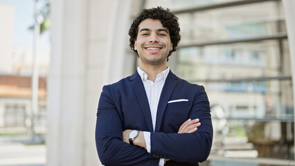 Young latin man business worker smiling confident standing with arms crossed gesture at street