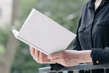 White book cover in woman's hands. Book cover for mock up - Powered by Adobe