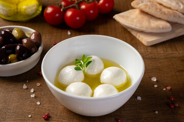 Labneh - yogurt balls with olive oil in a bowl on wooden background.