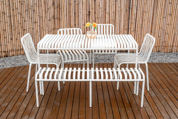 Outdoors white steel table and chairs on a wooden terrace in summer - 619730227
