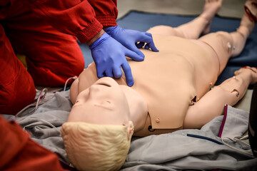 Paramedics simulate emergency intervention on medical training manikin - 619730408