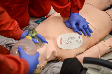 Paramedics simulate emergency intervention on medical training manikin - 619730425