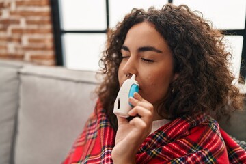 Young beautiful hispanic woman covering with blanket using nasal machine at home