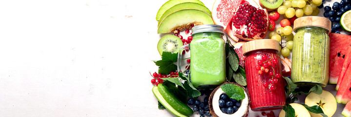 Fresh fruit and vegetable smoothies or juice  with various ingredients on light background.