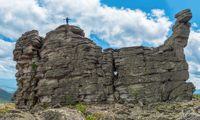 Fototapeta premium The person climbed to the top of the stone cliff and spreading arms.