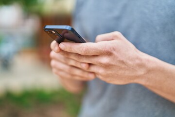 Young caucasian man using smartphone at park
