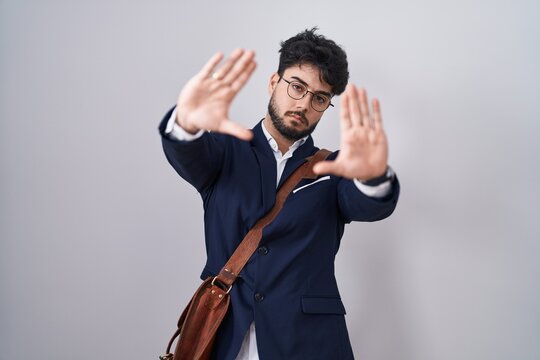 Hispanic man with beard wearing business clothes doing frame using hands palms and fingers, camera perspective