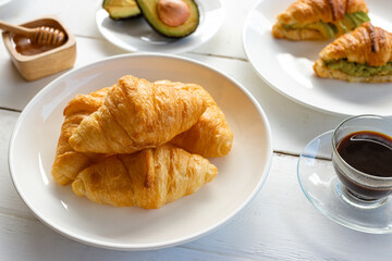 Croissant with egg,avocado on white dish and honey, coffee. breakfast and healthy food concept..