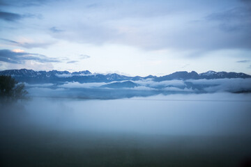Cloudy weather in the mountains. Panorama of the mountain range. Floating clouds. View of the mountains through the clouds. Closed peaks of the mountain range. Bird's-eye view.