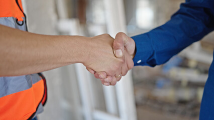 Two men builder and architect shake hands at construction site