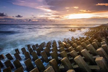 Obraz premium Wave breaker at the sea side at Ban Pecah beach, Tanjung Piandang Perak taken during cloudy sunset with long exposure.