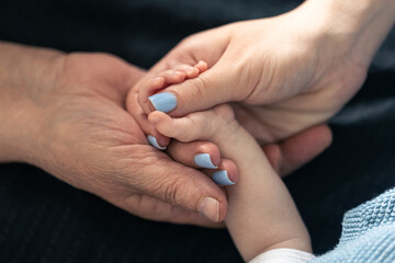 Close-up, hands of a baby, mother and grandmother.