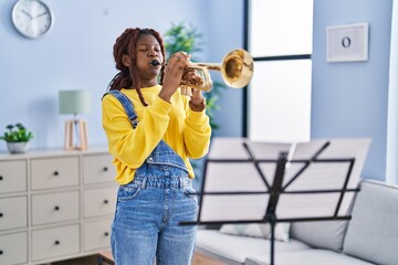 African american woman musician playing trumpet at home